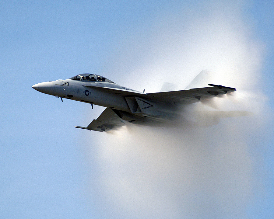 9. An F/A-18F Super Hornet Fighter Jet, September 25, 2004. United States Navy. Naval Air Station Oceana, Commonwealth of Virginia, USA. Reaching the sound barrier, breaking the sound barrier: Flying at transonic speeds (flying transonically) -- speeds varying near and at the speed of sound (supersonic) -- can generate impressive condensation clouds caused by the Prandtl-Glauert Singularity. For a scientific explanation, see Professor M. S. Cramer's Gallery of Fluid Mechanics, Prandtl-Glauert Singularity at <http://www.GalleryOfFluidMechanics.com/conden/pg_sing.htm>; and Foundations of Fluid Mechanics, Navier-Stokes Equations Potential Flows: Prandtl-Glauert Similarity Laws at <http://www.Navier-Stokes.net/nspfsim.htm>. Photo Credit: Photographer's Mate 2nd Class Daniel J. McLain, Navy NewsStand - Eye on the Fleet Photo Gallery (http://www.news.navy.mil/view_photos.asp, 040925-N-0295M-108), United States Navy (USN, http://www.navy.mil), United States Department of Defense (DoD, http://www.DefenseLink.mil or http://www.dod.gov), Government of the United States of America (USA).